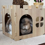 Two rabbits inside a wooden pet house with a castle design.