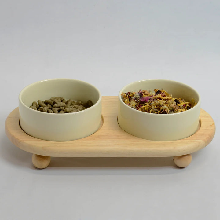 Two beige bowls for rabbits on a raised bamboo stand