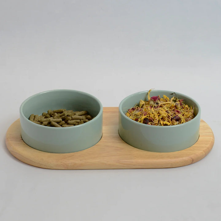 Two light green bowls for rabbits on a flat bamboo stand