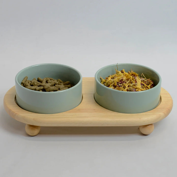 Two light green bowls for rabbits on a raised bamboo stand