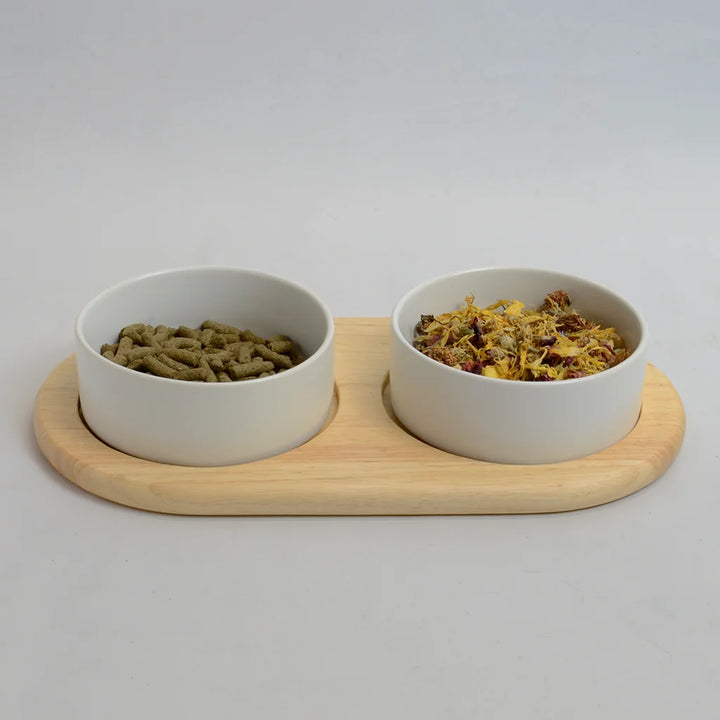 Two white bowls for rabbits on a flat bamboo stand