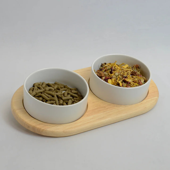 Two white bowls for rabbits on a inclined bamboo stand