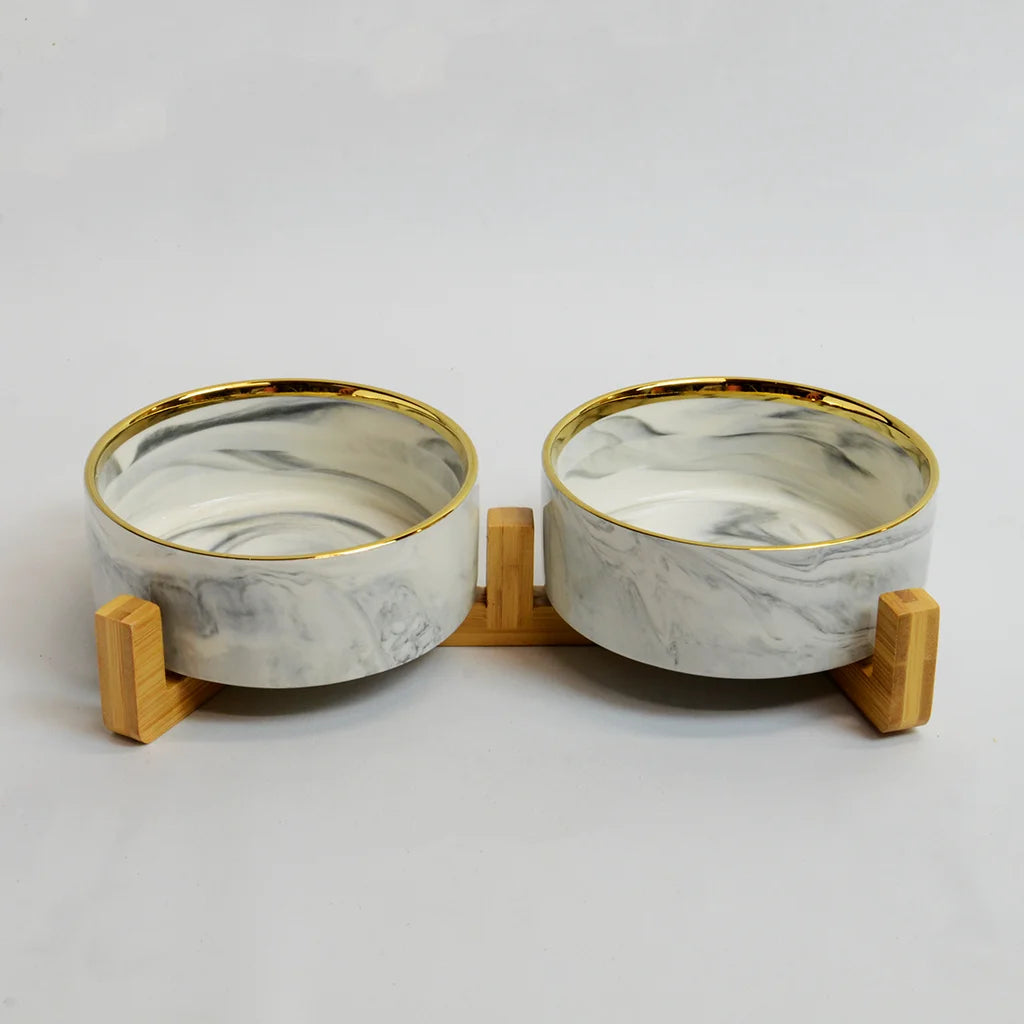 Two grey marble-look bowls with gold rims on a raised bamboo stand