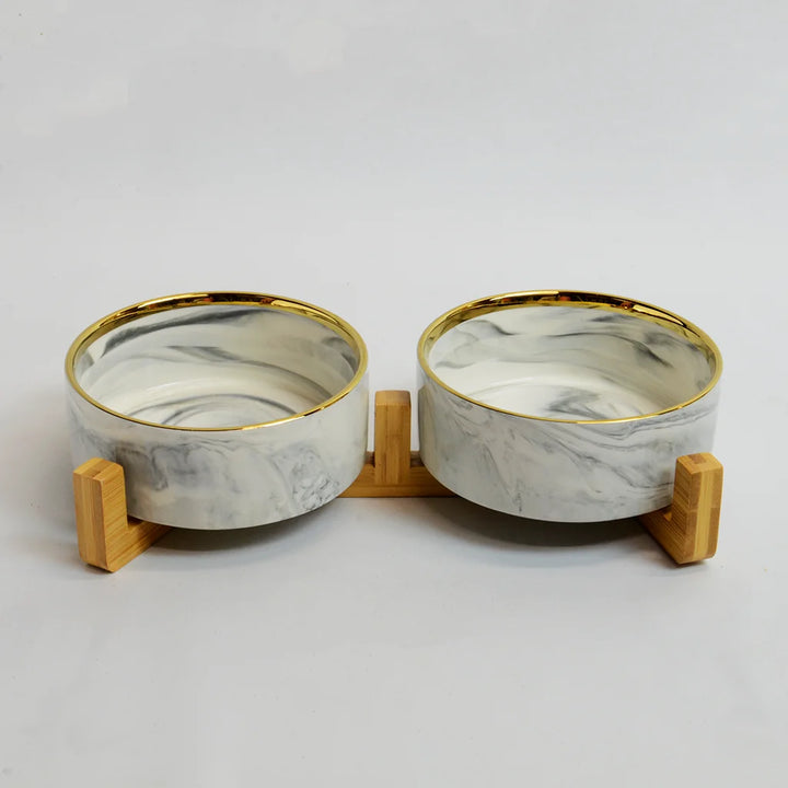 Two grey marble-look bowls with gold rims on a raised bamboo stand