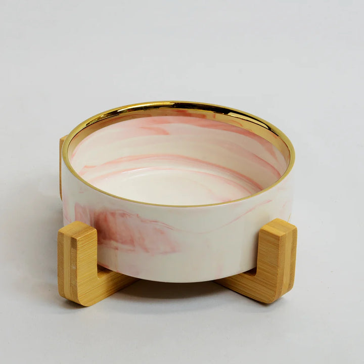 One pink marble-look bowl with gold rim on a raised bamboo stand