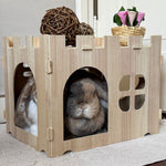 Wooden pet house with two rabbits inside on a carpeted floor.